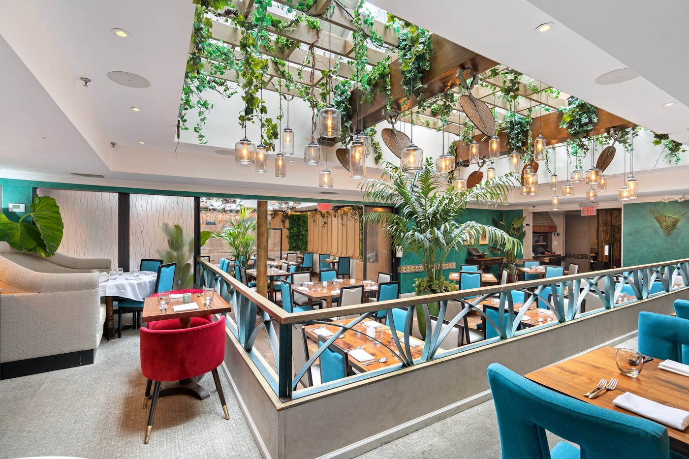 Victor’s Café dining rooms with skylights, tropical greenery, colorful seating, and pendant lights